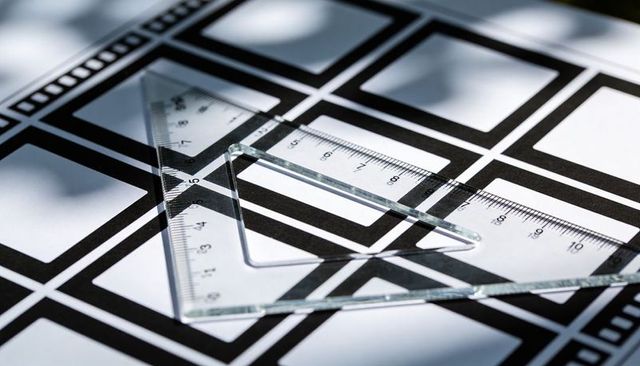 Overlapping transparent triangle rulers on monochrome grid showing centimeter scale
