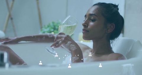 Relaxing in bubble bath holding wine glass, spa-style self-care and evening calm