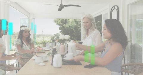 Multigenerational women pouring tea on sunlit porch during relaxed family and friends gathering