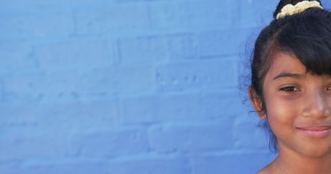 Young hispanic student smiling by blue background
