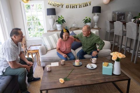 Celebrating senior woman's birthday in cozy living room with family, cake and roses