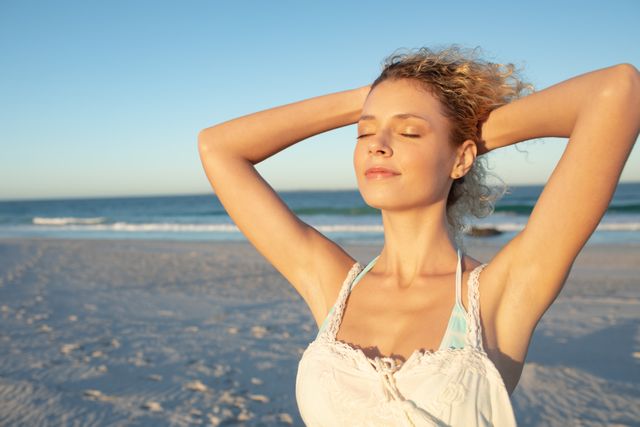Beautiful woman standing with eyes closed on the beach