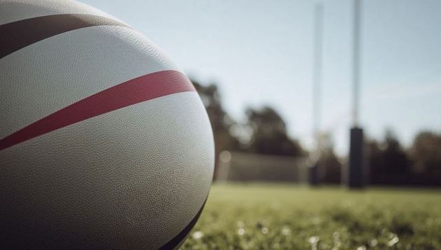 White Rugby Ball on Green Field with Goalposts Under Bright Sky