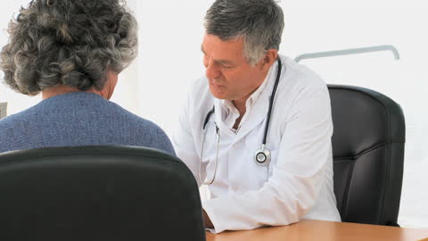 Doctor Consulting with Elderly Patient in Office