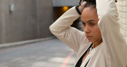 Focused African Woman Adjusting Hairstyle While Listening to Music in Urban Area - Download Free Stock Images Pikwizard.com