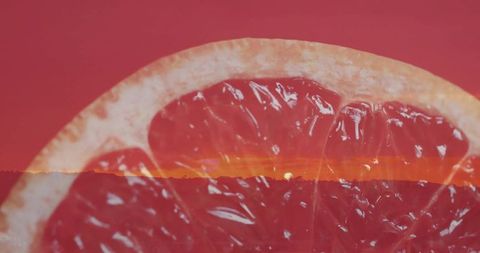 Grapefruit half with sunset horizon overlay vibrant close-up of citrus pulp