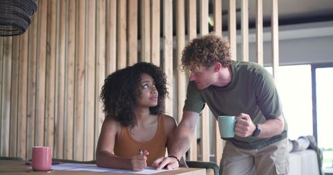 Young couple reviewing bills and planning at wooden table in modern open-plan living space