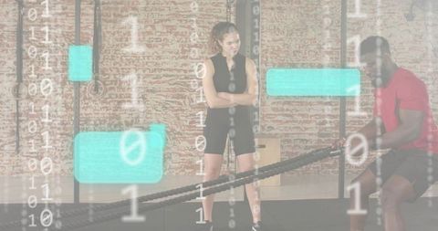 Trainer supervising partner doing battle ropes in brick gym with fitness data overlay
