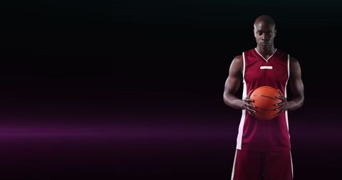 Basketball Player Holding Ball on Dark Background