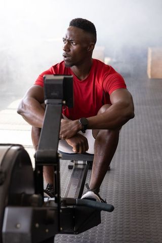 Determined African American Man Resting on Rowing Machine After Intense Cardio Workout