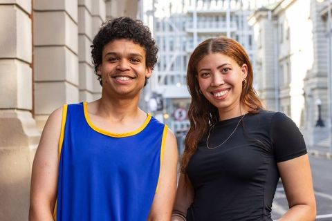 Smiling young couple standing on city street wearing casual athletic and stylish outfits