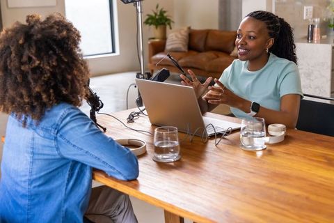 African american women recording podcast interview in cozy home studio
