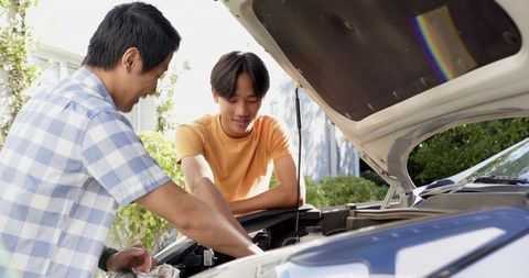 Father and Son Examining Car Engine Together in Driveway