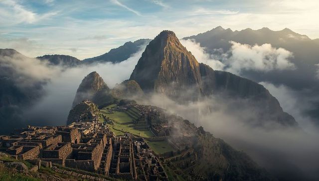 Machu picchu at dawn with mist rolling and sunlight illuminating ancient terraces