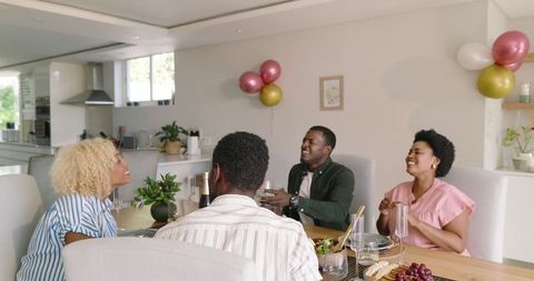 Cheerful Friends Laughing Together at Home Dining Table Celebration