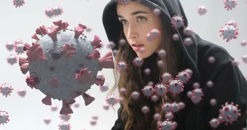 Young Woman in Hoodie Surrounded by Digital Coronavirus Models