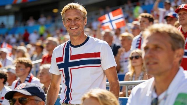 Smiling norwegian fan cheering in sunny stadium wearing flag-cross t-shirt and waving flag