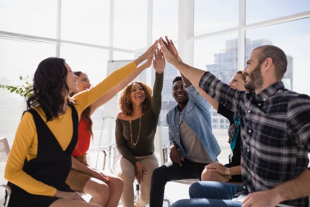 Group of happy executives giving high five to each other in office