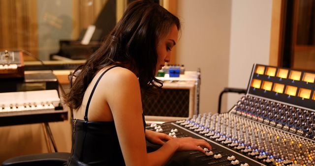 Focused caucasian female disc jockey using her music panel in studio room. Music, technology and lifestyle, unaltered.