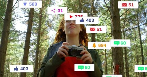 Young woman holding retro camera in pine forest with floating social media notification icons