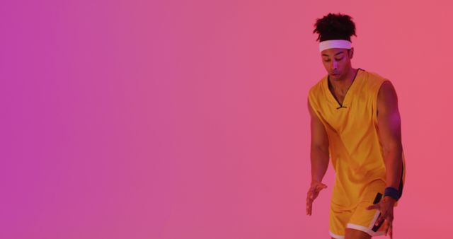 Image of biracial male basketball player throwing ball on orange to pink background. Sports and competition concept.