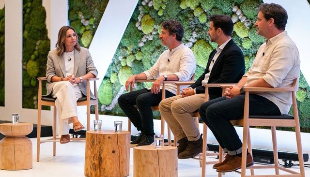 Moderator leading panel discussion with four experts on stage with moss wall backdrop