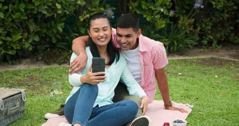 Asian Couple Taking Selfie During Relaxing Picnic Outdoors