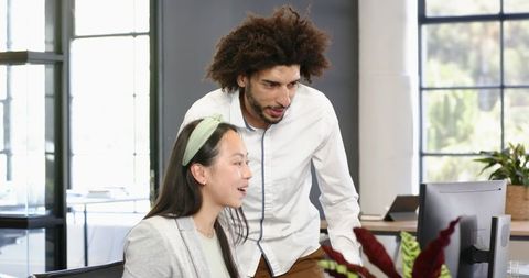 Colleagues Collaborating at Workstation in Modern Office