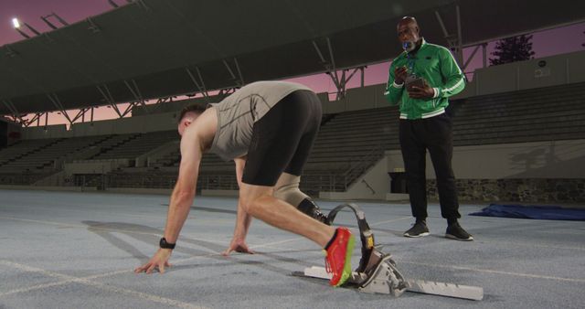 Diverse male coach and disabled male athlete with running blade getting ready to start a run. professional runner training at sports stadium.