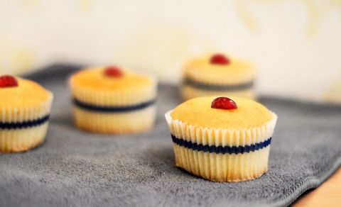 Vanilla cupcakes with cherry toppings on gray cloth