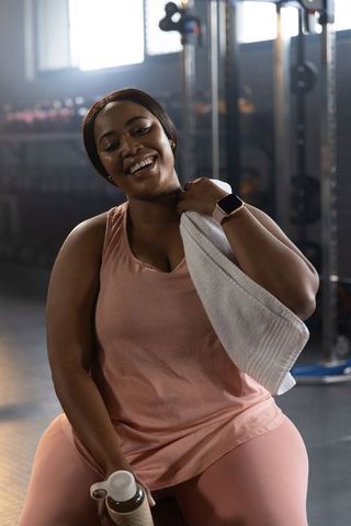 Smiling african american woman resting post-workout in gym wearing pink activewear