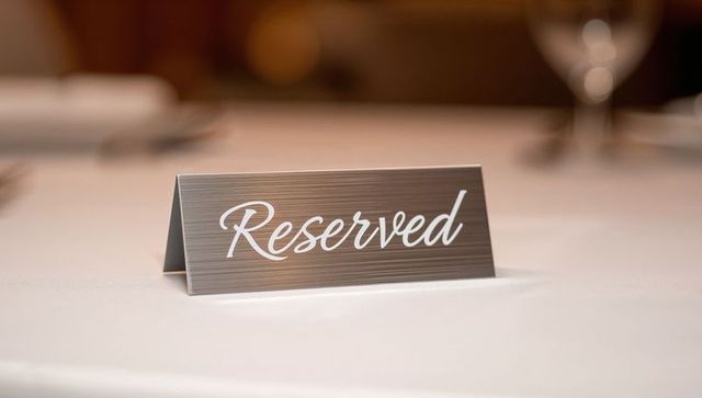 Elegant metal reserved sign on white tablecloth for banquet event seating and formal dining