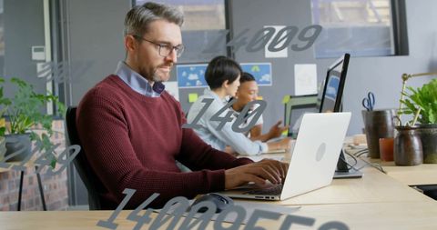 Caucasian Businessman Analyzing Data on Laptop in Modern Office