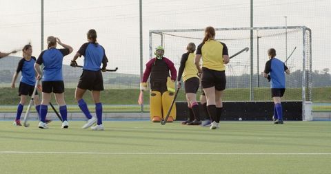 Female field hockey team competing on the turf field detail