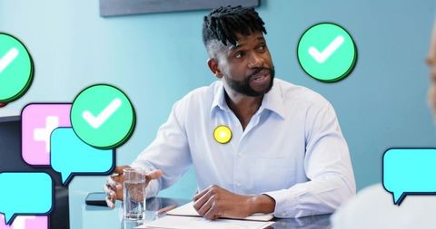 Businessman speaking and gesturing during team meeting with chat icons and approval marks