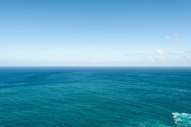 Expansive view of a calm ocean meeting a clear blue sky. Ideal for depicting travel destinations, serenity, nature wallpapers, or backgrounds in digital projects and advertisements promoting relaxation, vacations, or natural beauty.