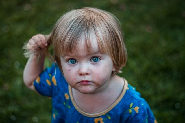 Curious Blonde Toddler Playing Outdoors with Intense Blue Eyes - Download Free Stock Photos Pikwizard.com