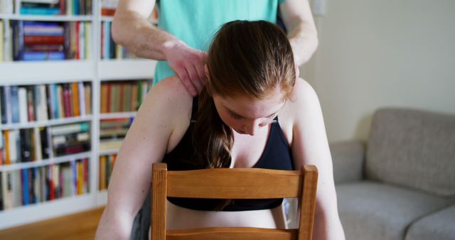 Woman receiving neck massage in home. Likely to be used for topics related to healthcare, relaxation, self-care, physical therapy, muscle relief, and pain relief at home. Promotes holistic wellness and personal healthcare.