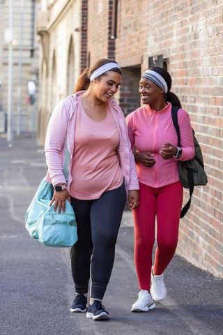 African american women walking and laughing after workout in urban athleisure wearing pink