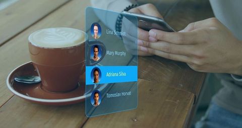 Man scrolling smartphone viewing holographic contact list beside cappuccino on wooden table