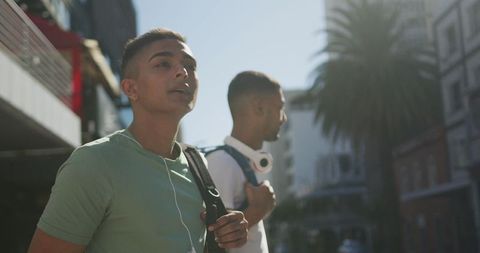 Young Men Standing on Urban Street with Backpacks and Earphones - Download Free Stock Images Pikwizard.com
