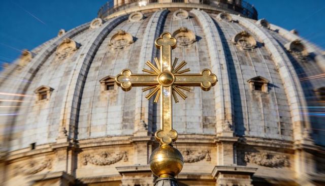 Gleaming gilded cross atop golden orb over historic cathedral dome with sunburst reflection