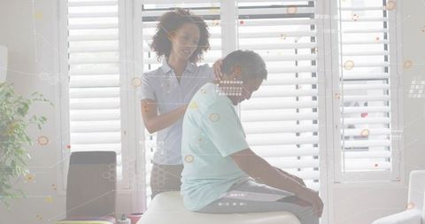 Caregiver massaging senior man neck on clinic table for rehabilitation and shoulder relief