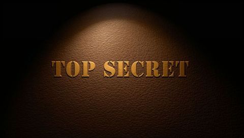 Gold embossed top secret lettering on dark brown leather under spotlight
