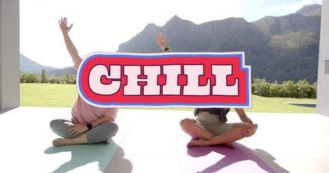 Woman and teen holding chill sign during outdoor yoga on terrace with mountain view