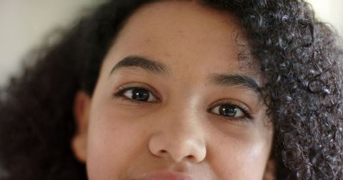 Gazing youth with natural curly hair closeup portrait expressive eyes and warm lighting