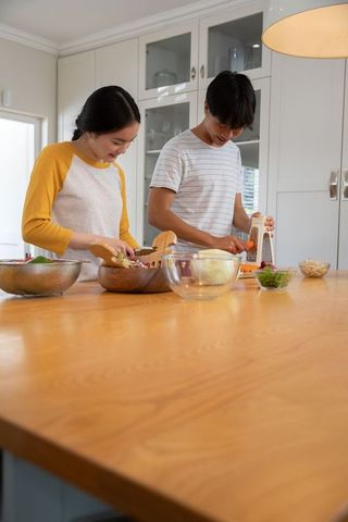 Asian couple preparing healthy meal in modern kitchen