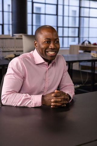 Smiling Professional in Pink Shirt at Modern Office Desk