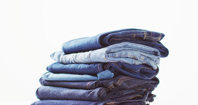 Close up of folded jeans with different shades on white background with copy space. Denim day, material, style and design concept.