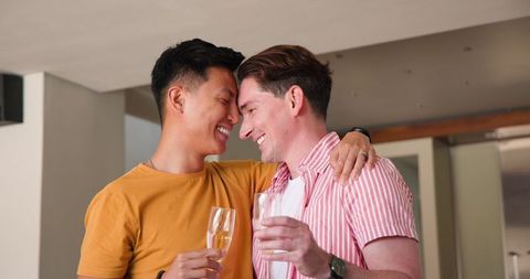 Happy Gay Couple Toasting with Champagne at Home